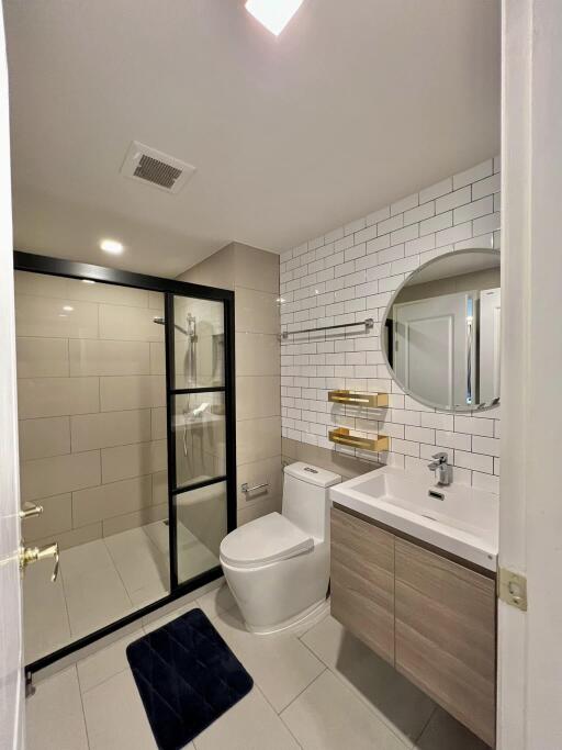 Modern bathroom with glass shower, round mirror, and elegant fixtures