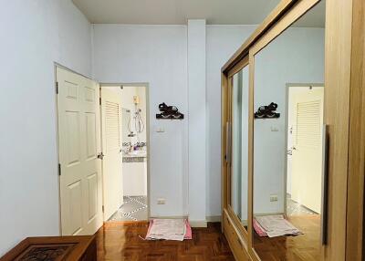Bedroom with wooden flooring, mirrored wardrobe, and decorative chest