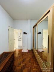 Bedroom with wooden flooring, mirrored wardrobe, and decorative chest