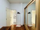 Bedroom with wooden flooring, mirrored wardrobe, and decorative chest