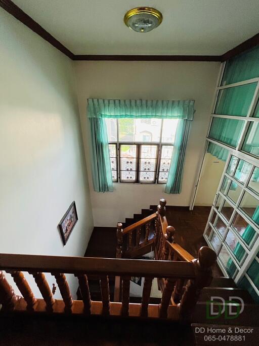 View of staircase with wooden railing and window