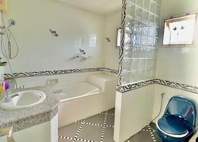 Well-lit bathroom with bathtub, window, blue toilet, and sink