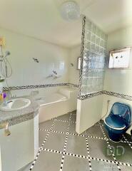 Well-lit bathroom with bathtub, window, blue toilet, and sink