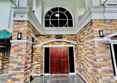 Front view of the building entrance with a wooden door and multicolored stone facade