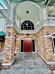 Front view of the building entrance with a wooden door and multicolored stone facade