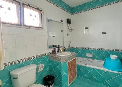 Bathroom with turquoise tile design featuring a toilet, sink with mirror, and bathtub