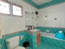 Bathroom with turquoise tile design featuring a toilet, sink with mirror, and bathtub