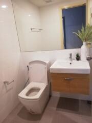 Modern bathroom with white toilet, wall-mounted sink, and decorative plants