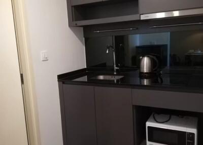 Modern kitchen with dark cabinets, sink, kettle, and microwave oven