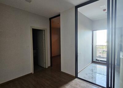 A room with wooden flooring and a sliding glass door leading to a small balcony