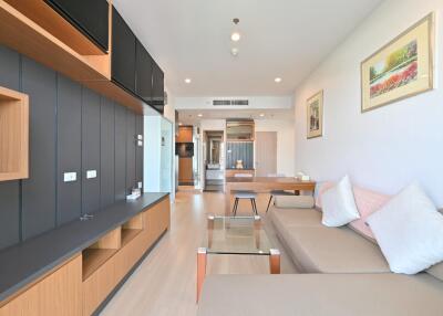 Modern living room with a beige sofa, glass coffee table, and wooden television unit