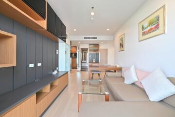 Modern living room with a beige sofa, glass coffee table, and wooden television unit