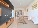 Modern living room with a beige sofa, glass coffee table, and wooden television unit