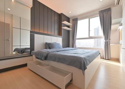 Modern bedroom with wooden flooring, large window, and built-in storage