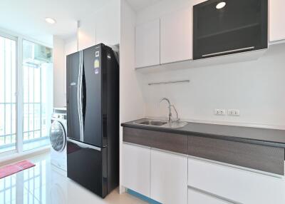 Modern kitchen with black refrigerator, sink, and washing machine