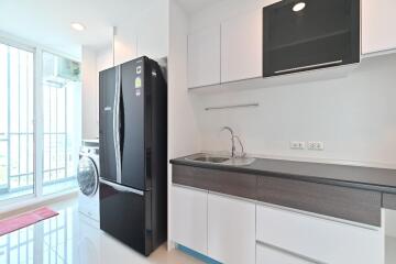 Modern kitchen with black refrigerator, sink, and washing machine
