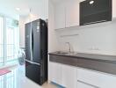 Modern kitchen with black refrigerator, sink, and washing machine