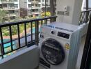 Balcony with washing machine and view of pool and neighboring buildings