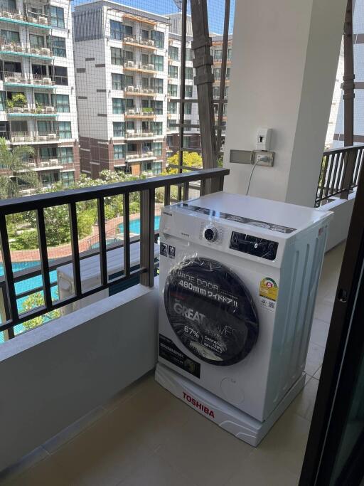 Balcony with washing machine and view of pool and neighboring buildings