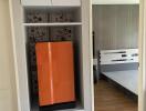 Bedroom with a closet and a bright orange refrigerator
