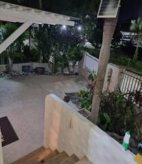 Nighttime view of an outdoor area with plants, pavement, and steps