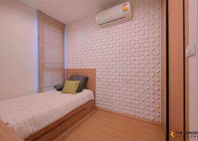 Modern bedroom with single bed, wall-mounted air conditioner, and textured wall