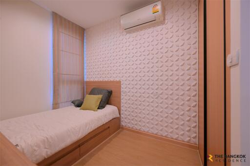 Modern bedroom with single bed, wall-mounted air conditioner, and textured wall
