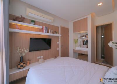 Modern bedroom with wall-mounted TV, shelves, and en-suite bathroom