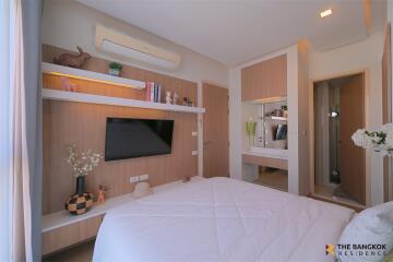 Modern bedroom with wall-mounted TV, shelves, and en-suite bathroom