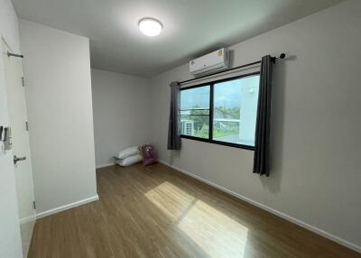 Minimalist bedroom with wooden flooring, window and AC unit