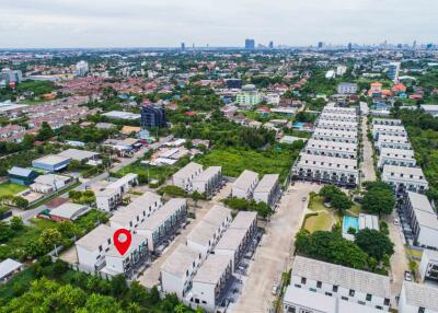 Aerial view of a residential neighborhood with multiple apartment buildings, lush greenery, and a small pool.