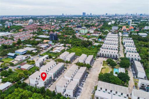 Aerial view of a residential neighborhood with multiple apartment buildings, lush greenery, and a small pool.