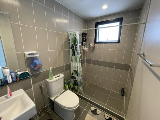 Modern bathroom with tiled walls and floor, featuring a walk-in shower, toilet, and sink.