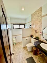 Modern bathroom with tiled walls, a round mirror, and a window