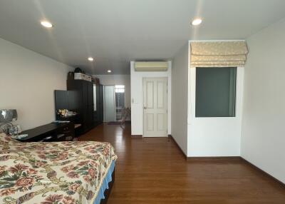 Spacious bedroom with wooden floors, wardrobe, and air conditioning