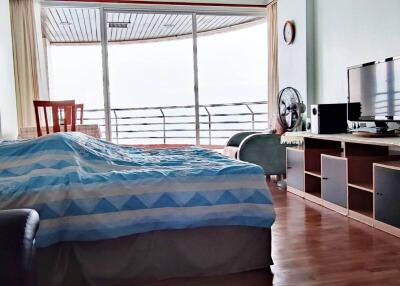 Spacious bedroom with balcony view, bed, TV stand, and wooden flooring