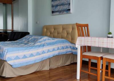 Bedroom with wooden floor, bed, and small dining table with two chairs