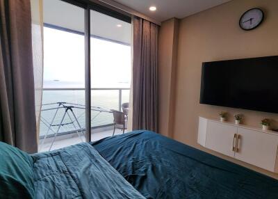 Bedroom with balcony view, TV, and seating area