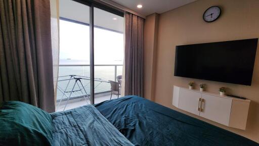 Bedroom with balcony view, TV, and seating area