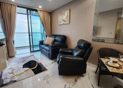 Comfortable living room with leather chairs, wall-mounted TV, and large windows