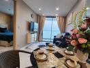 Modern living room with adjacent bedroom, featuring a dining area and ocean view