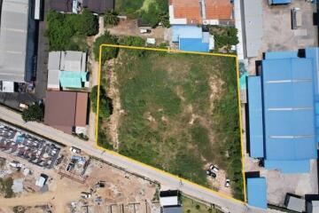 Aerial view of a vacant lot bordered in yellow, surrounded by buildings and a road.