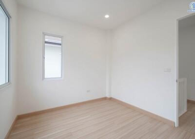 Empty, well-lit bedroom with wooden flooring