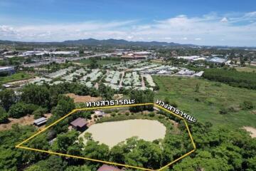 Aerial view of a property with a pond and surrounding greenery