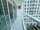 Modern apartment balcony with glass doors and view of adjacent building