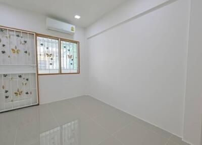 Small empty bedroom with tiled floor and decorated window grills