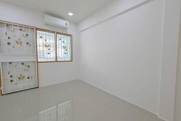 Small empty bedroom with tiled floor and decorated window grills