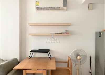 Living room with air conditioner, shelves, table, chair, fan, and partial view of a couch.