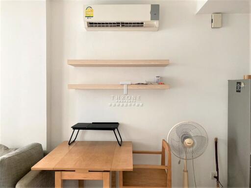 Living room with air conditioner, shelves, table, chair, fan, and partial view of a couch.