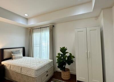 Spacious bedroom with bed, wardrobe, and large windows